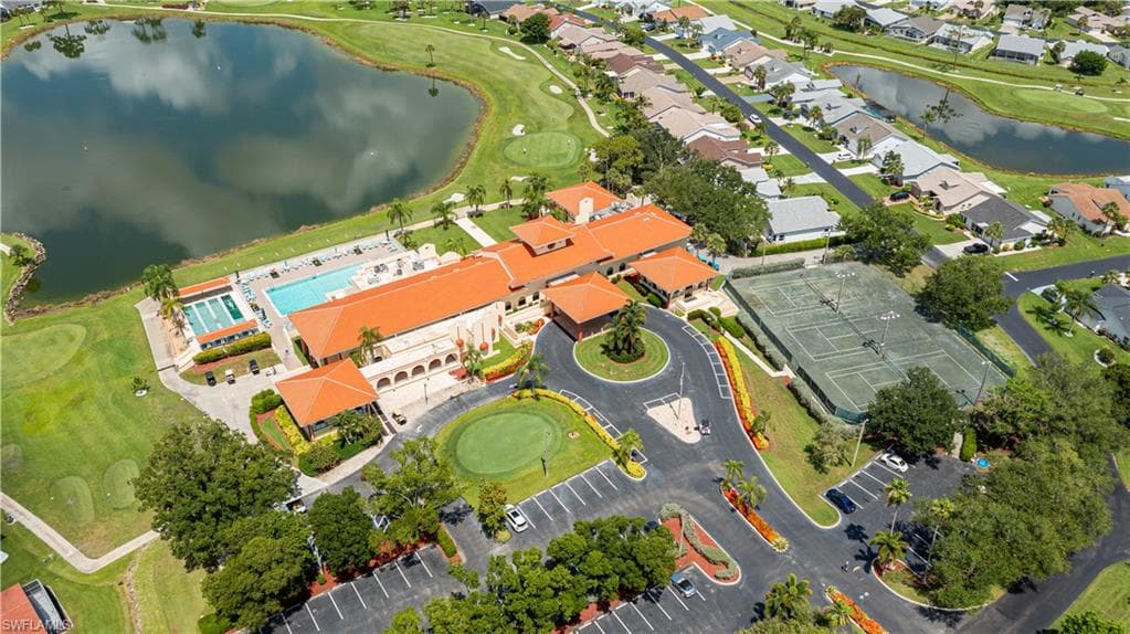 Mediterranean-style building with a terracotta tile roof, featuring multiple swimming pools, tennis courts, and a putting green, surrounded by a golf course and a lake