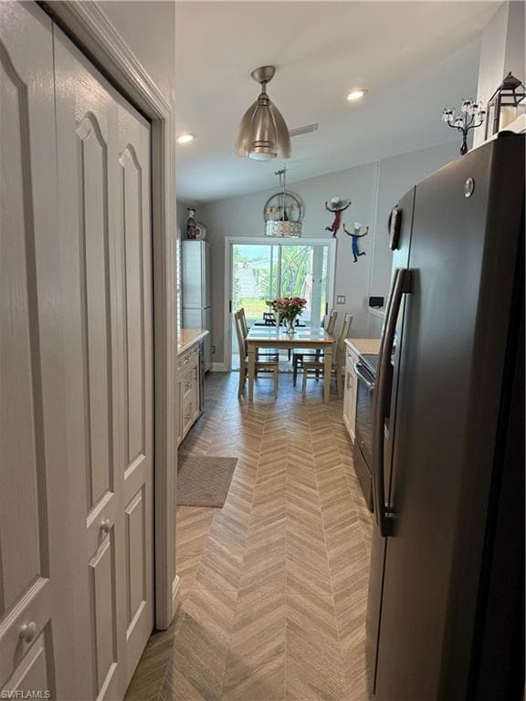 Kitchen featuring herringbone-patterned flooring, vaulted ceiling with recessed lighting and ceiling fan, and stainless steel appliances