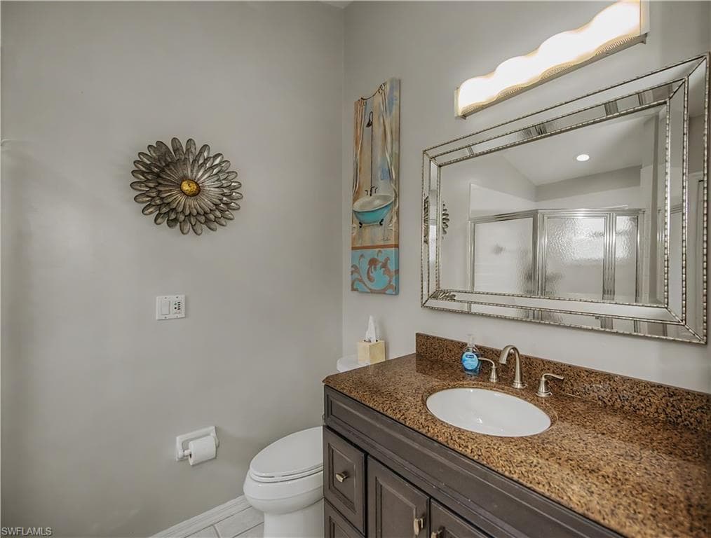 Bathroom vanity featuring a polished granite countertop with an undermount sink and brushed nickel faucet