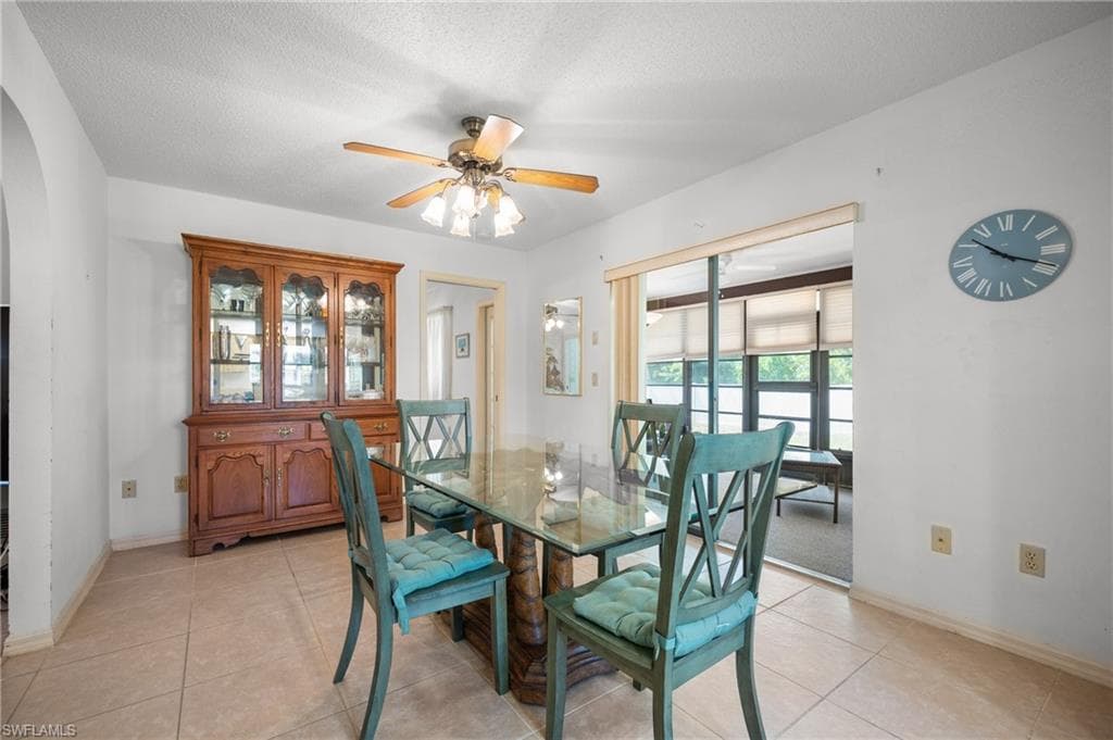 Dining area featuring ceramic tile flooring, a ceiling fan with integrated lighting, and a sliding glass door leading to an enclosed porch