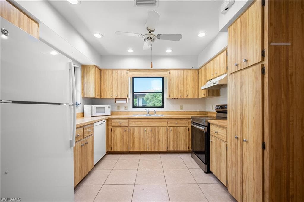 U-shaped kitchen featuring light wood cabinetry, light-toned countertops, and tile flooring