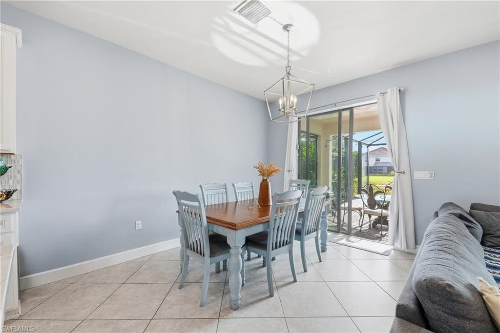 Dining area featuring a contemporary chandelier, tile flooring, and sliding glass doors opening to a screened outdoor space