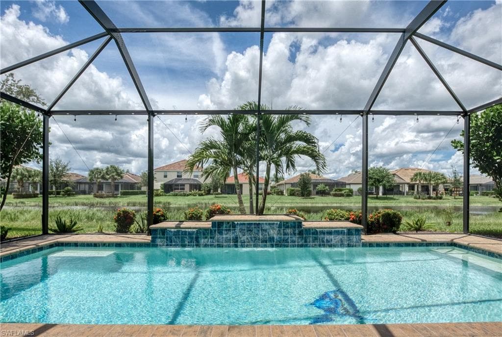 Screened-in pool area featuring a rectangular swimming pool with an integrated waterfall feature and tiled accents