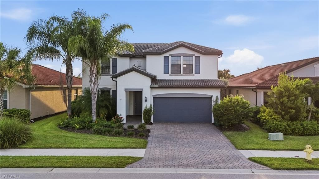 Two-story stucco residence featuring a tile roof and decorative window shutters