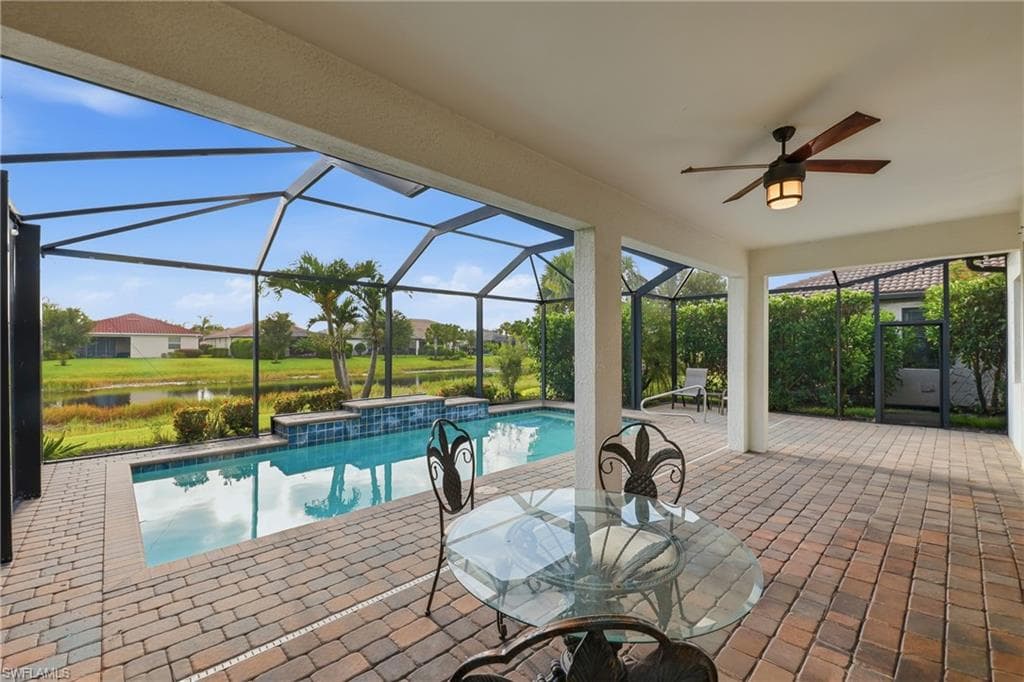 Screened lanai featuring a swimming pool with a stone waterfall feature, a paved patio, and a ceiling fan with integrated lighting