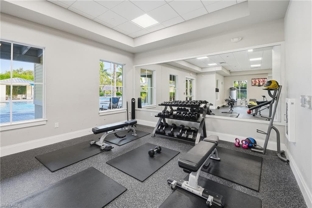Fitness center featuring a large wall mirror, recessed lighting, and rubberized flooring