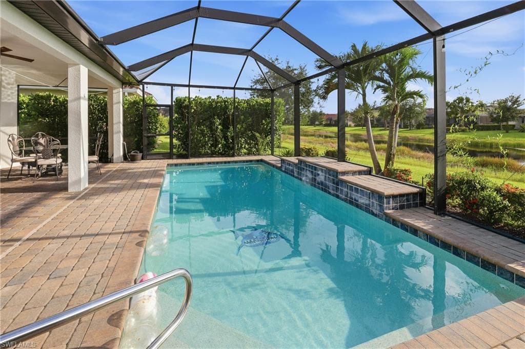 Screened-in pool deck featuring a swimming pool with steps, a paved patio, and covered lanai area