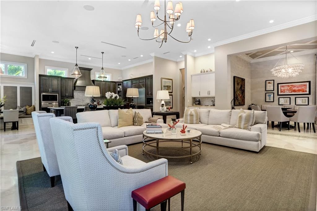 Open-concept living area featuring a coffered ceiling with recessed lighting, a contemporary chandelier, and wood-finish cabinetry in the kitchen