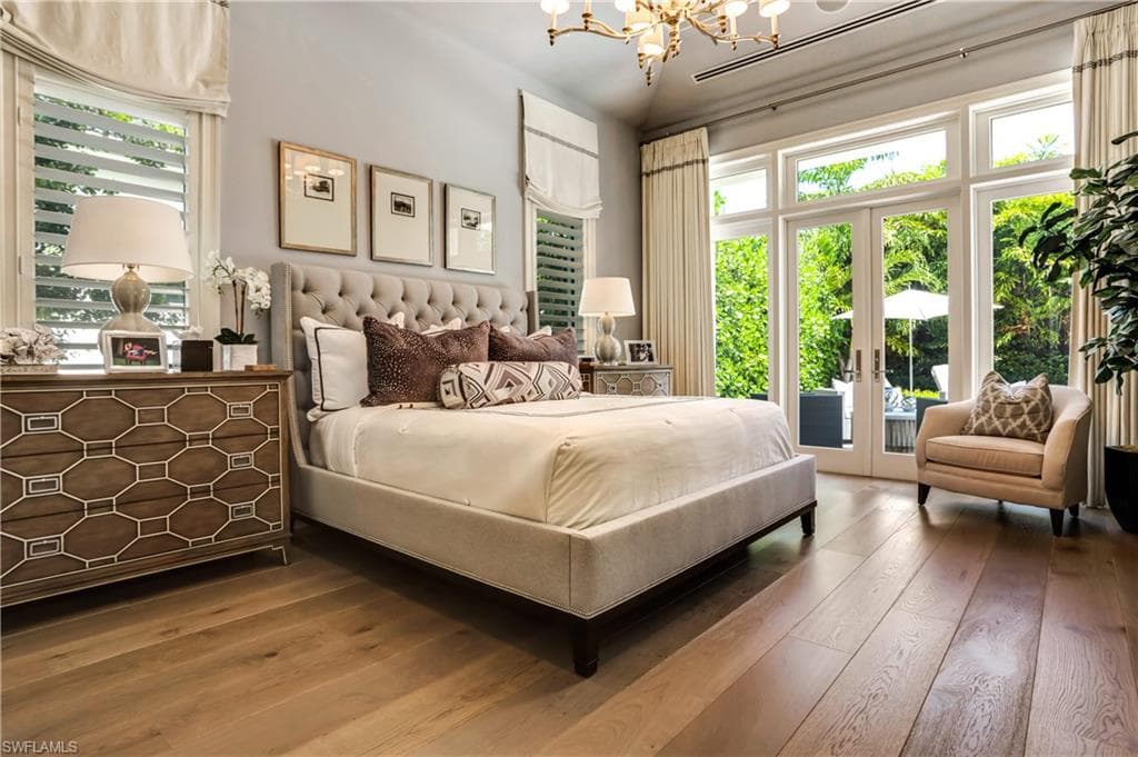 Spacious bedroom featuring wide plank wood flooring, a tufted headboard, and abundant natural light from multiple windows
