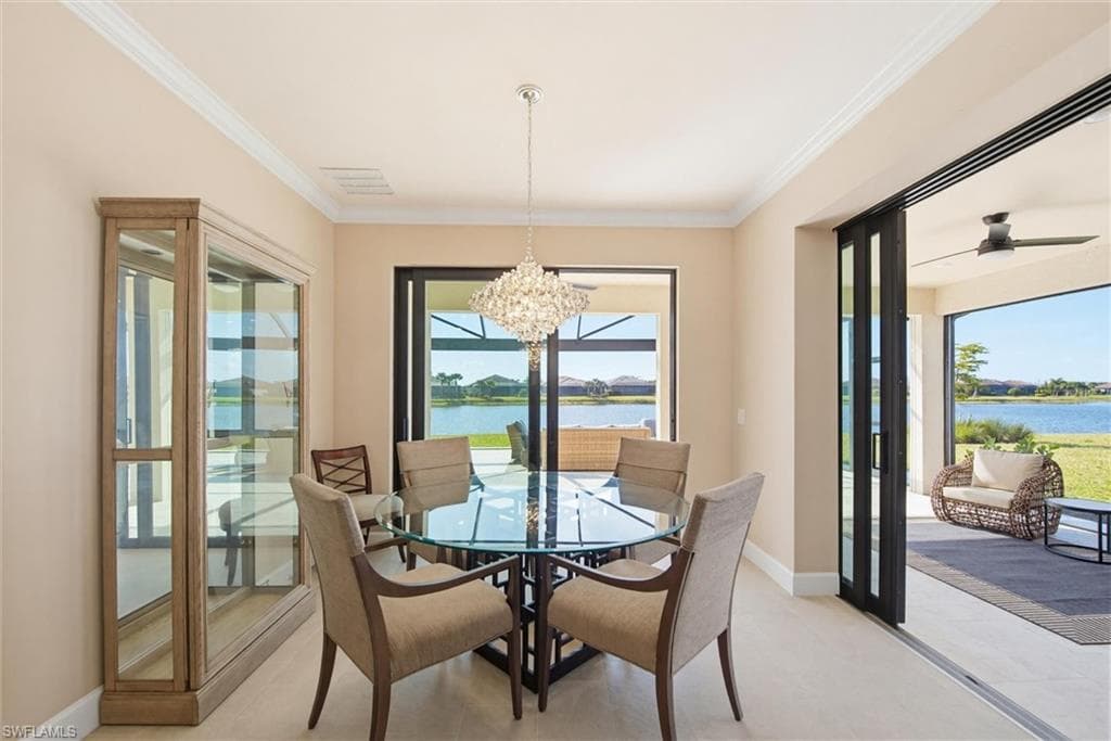 Dining space featuring hanging lights, a water view, crown molding, and a ceiling fan
