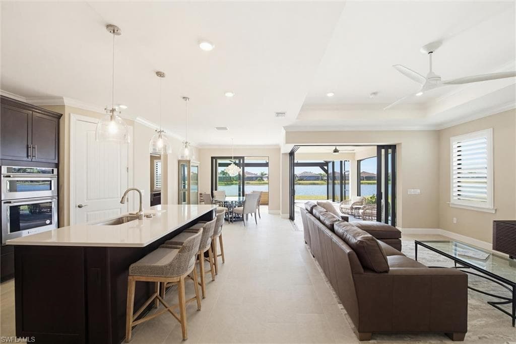 Kitchen with dark wood finish cabinets, a kitchen bar, a center island with sink, open floor plan, and a water view