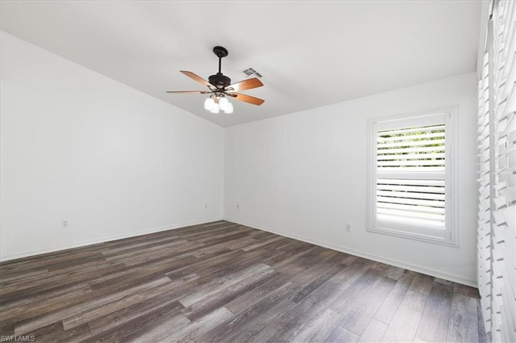 Spacious room featuring wood-finish flooring, a ceiling fan with integrated lighting, and a window with plantation shutters