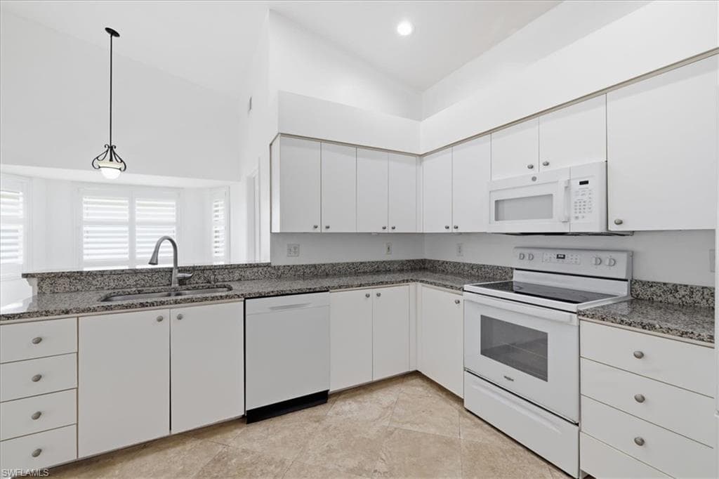 Kitchen featuring white cabinetry, speckled countertops, stainless steel sink, and light-toned tile flooring