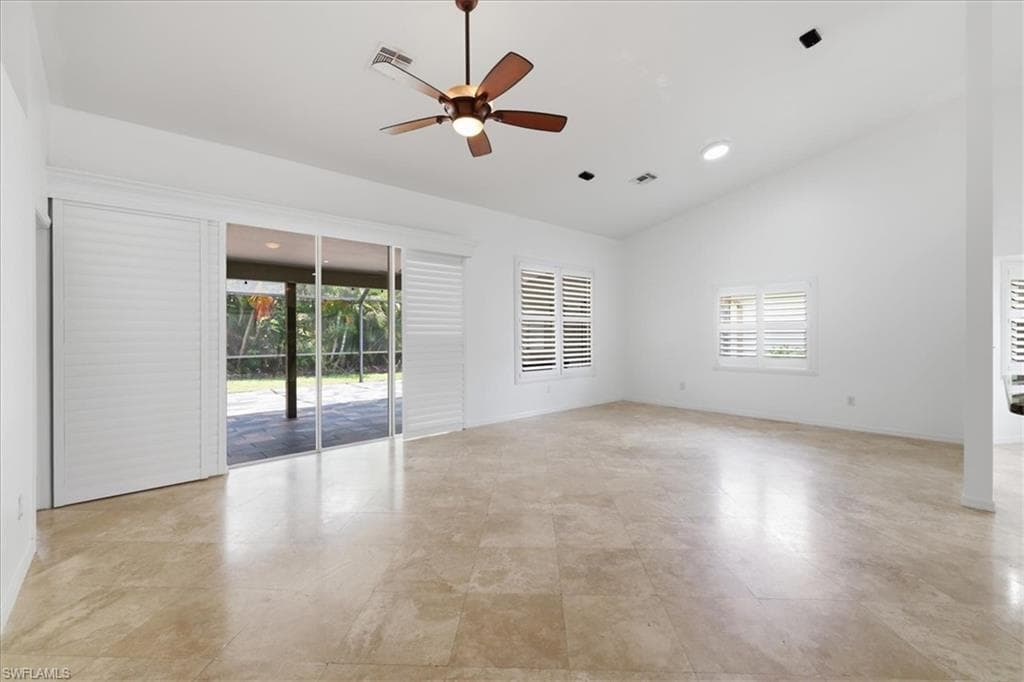 Expansive interior space featuring a vaulted ceiling and light-toned tile flooring