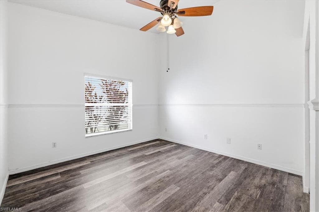 Interior room with wood-finish flooring, white walls, and a vaulted ceiling