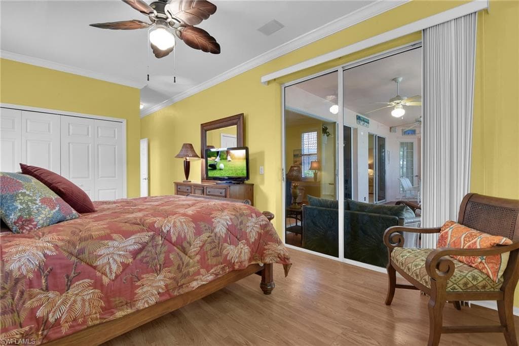 Spacious room featuring wood-finish flooring, a ceiling fan, and crown molding