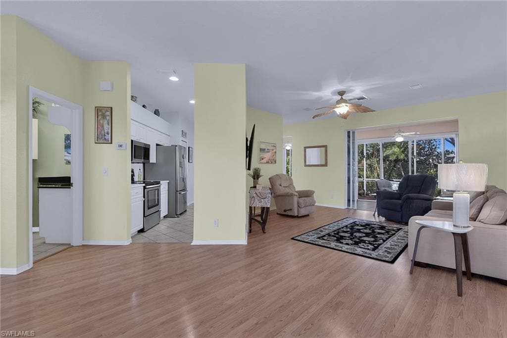 Wood-finish flooring throughout, stainless steel kitchen appliances, ceiling fans, and sliders to the exterior