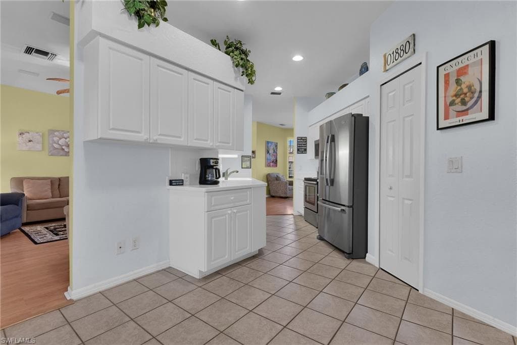 Kitchen area featuring tile flooring, white cabinetry, recessed lighting, and stainless steel appliances