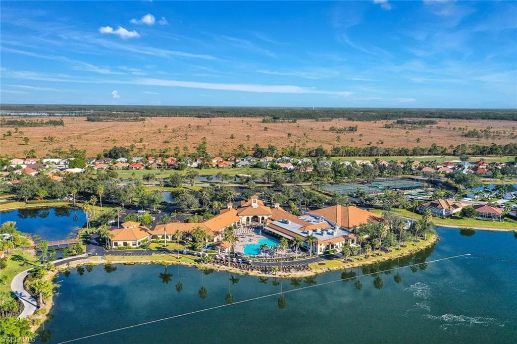 Expansive property featuring a central clubhouse with a swimming pool, multiple tennis courts, and surrounding residential structures