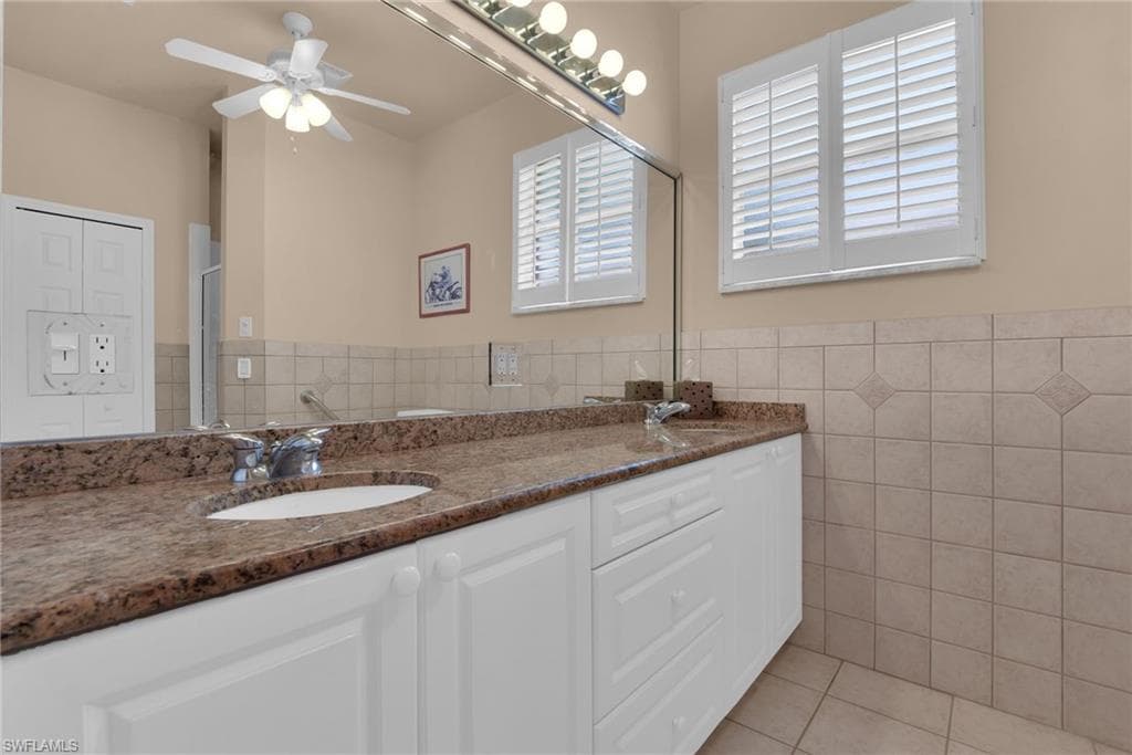 Bathroom vanity featuring a granite countertop, dual undermount sinks, and white shaker-style cabinetry