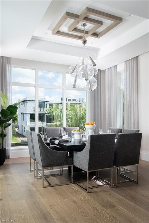 Dining area featuring a contemporary chandelier, wood-finish flooring, large windows, and a decorative tray ceiling with a geometric wood accent