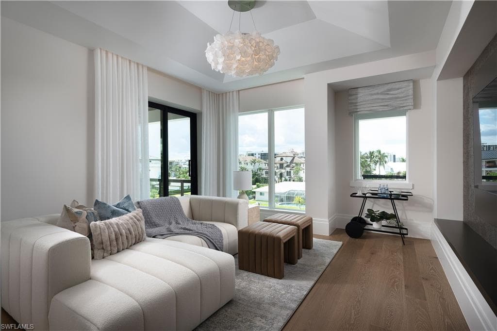 Spacious room featuring wood-finish flooring, a coffered ceiling with a modern chandelier, and multiple windows with white drapery