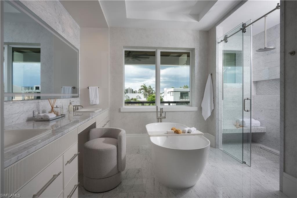 Contemporary bathroom featuring a freestanding soaking tub, a frameless glass shower enclosure with a built-in bench, a dual-sink vanity with stone countertops, and large format floor tiling