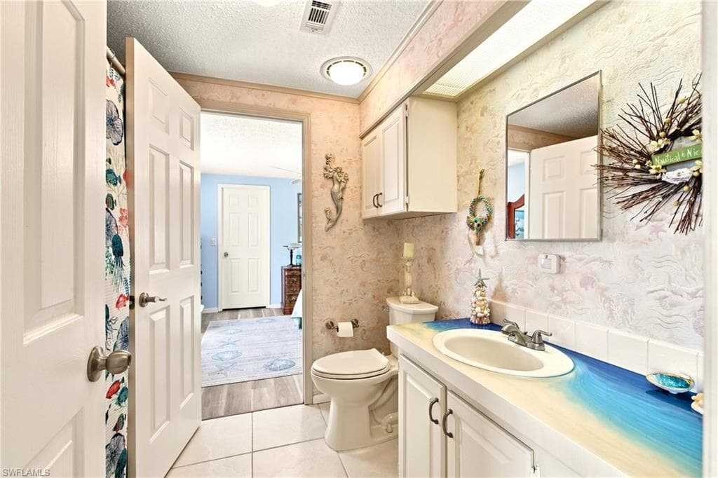 Bathroom featuring a vanity with an integrated sink, white cabinetry, and a wall-mounted mirror