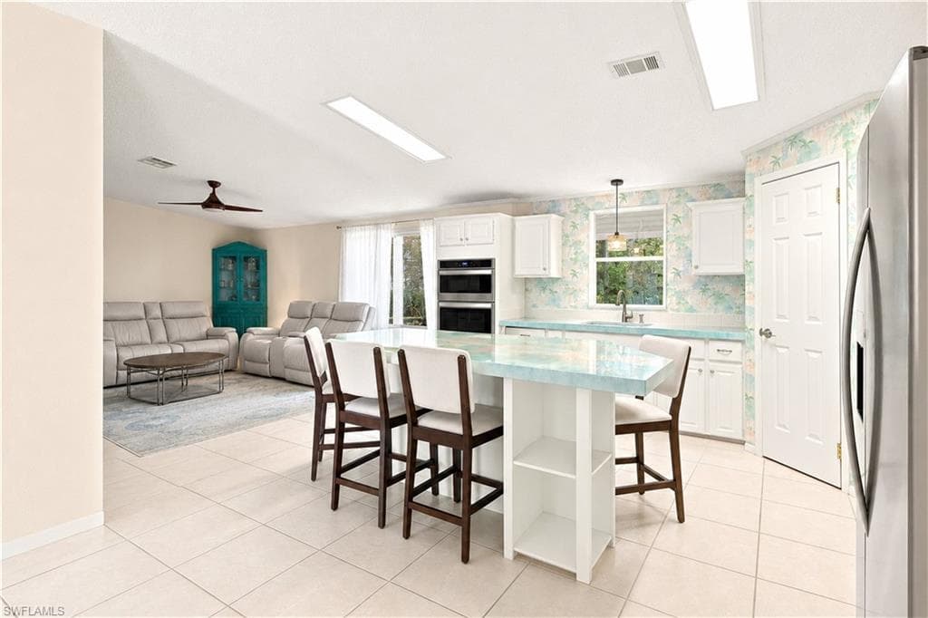 Open-concept kitchen featuring an island with seating, integrated double ovens, and tile flooring