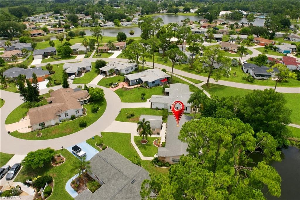 Residential property with a light gray shingled roof, featuring mature landscaping and a partial water frontage