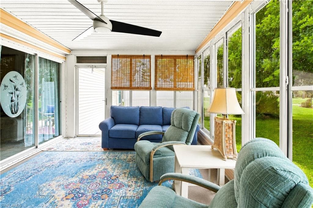 Screened-in porch featuring a ceiling fan, sliding glass doors, white paneled ceiling, and wood-finish blinds