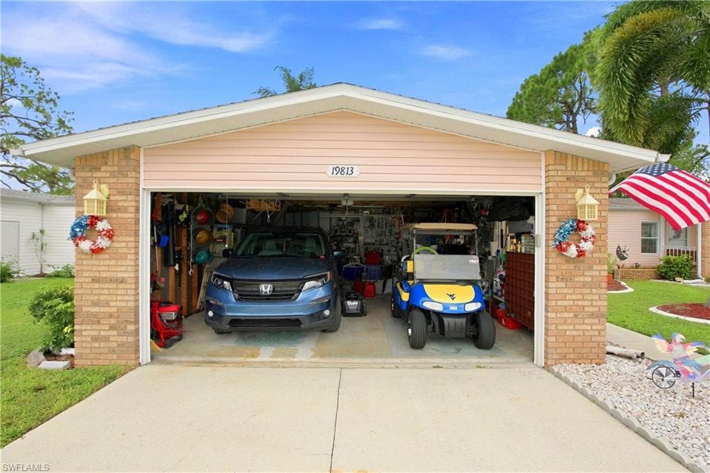Attached two-car garage featuring a beige brick exterior, light pink horizontal siding, and a concrete driveway