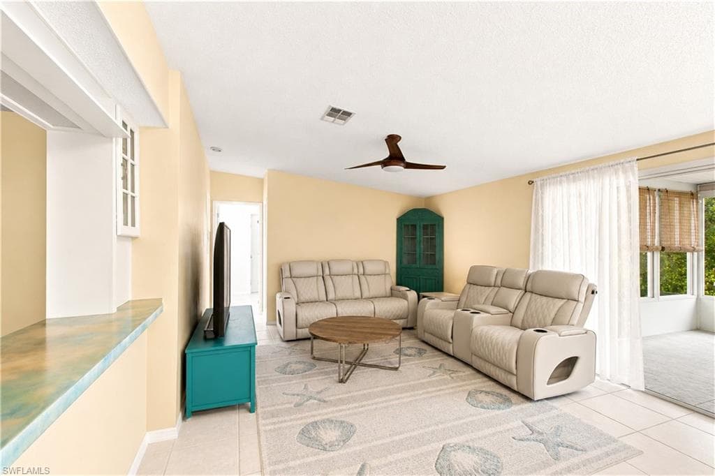 Spacious living area featuring tile flooring, a sloped ceiling, and a ceiling fan
