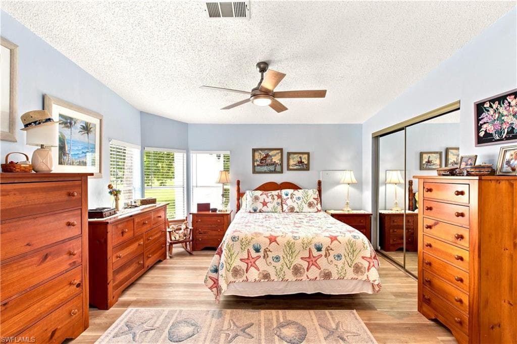 Bedroom featuring wood-finish flooring, a ceiling fan, and multiple windows with blinds