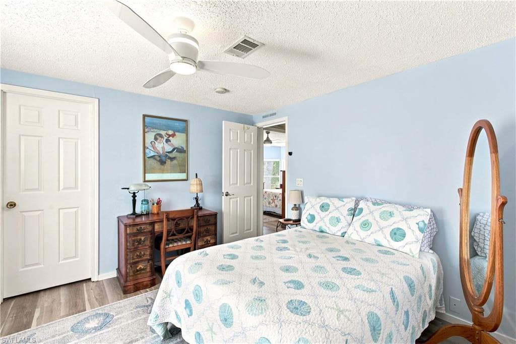 Bedroom featuring wood-finish flooring, a ceiling fan with integrated lighting, and multiple doors with classic paneling