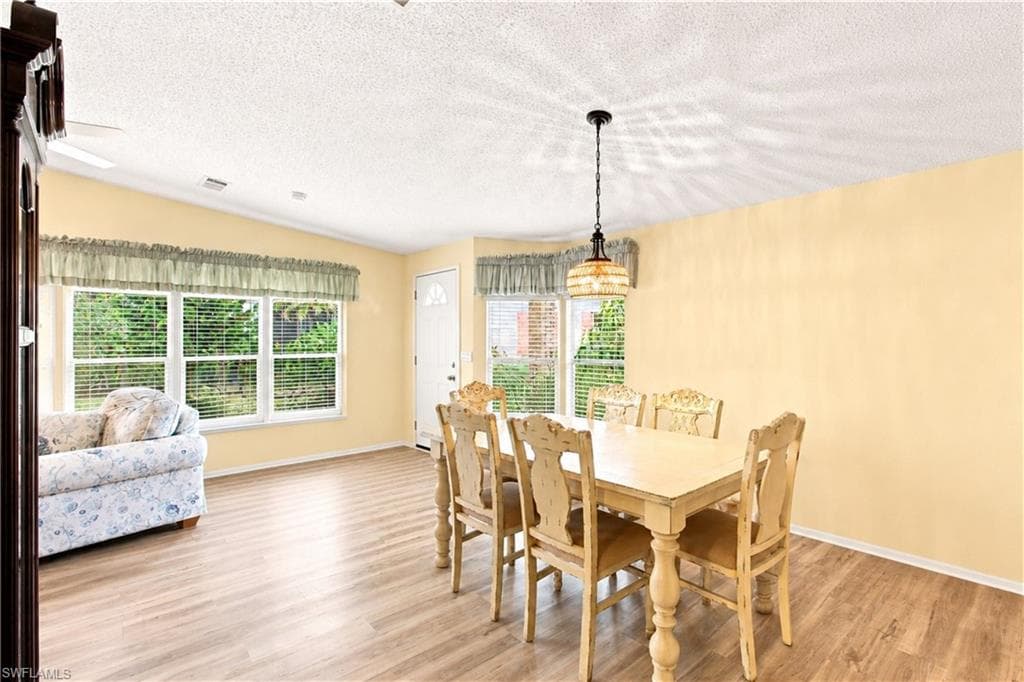 Expansive living space featuring wood-finish flooring, a ceiling fan, and multiple windows with horizontal blinds