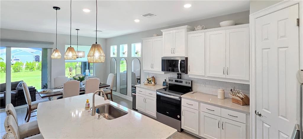 Gourmet kitchen featuring a large island with seating, stainless steel appliances, white cabinetry, and a spacious walk-in pantry