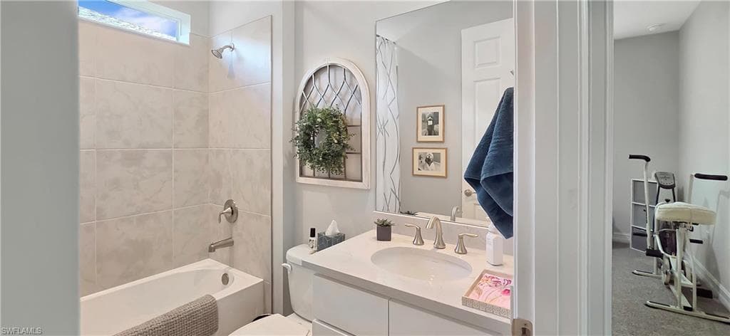 Bathroom featuring a white bathtub with subway tile surround, a single vanity with an undermount sink, and a large wall mirror
