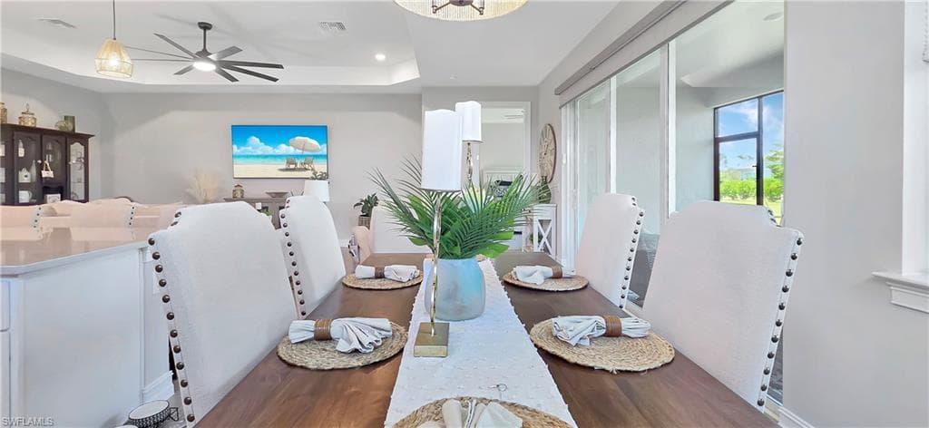 Expansive kitchen and dining area featuring light wood-finish flooring, recessed lighting, and a tray ceiling
