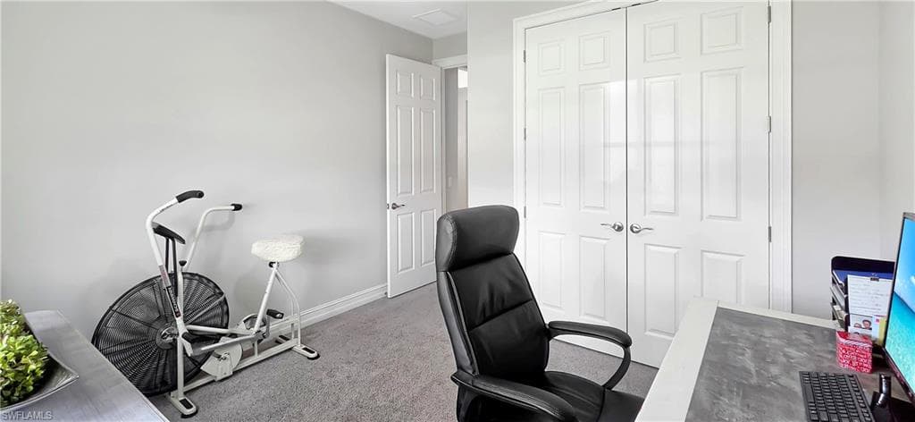Interior room featuring soft gray wall paint, light gray carpeting, and white baseboards