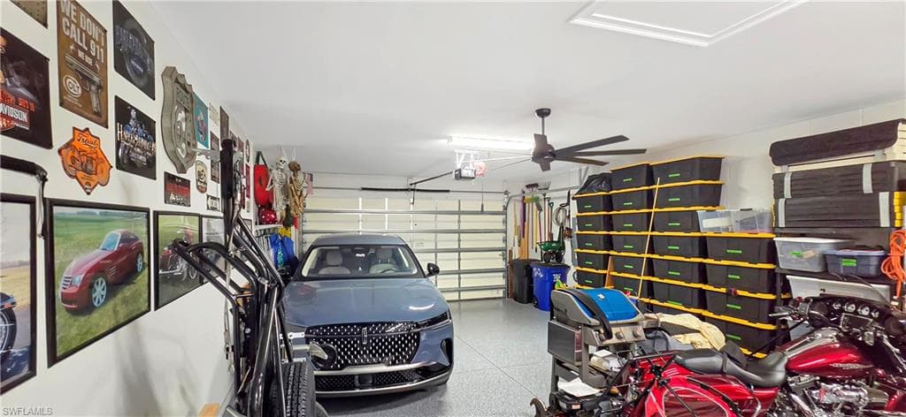Three-car garage featuring an epoxy floor, dual garage door openers, and a ceiling fan