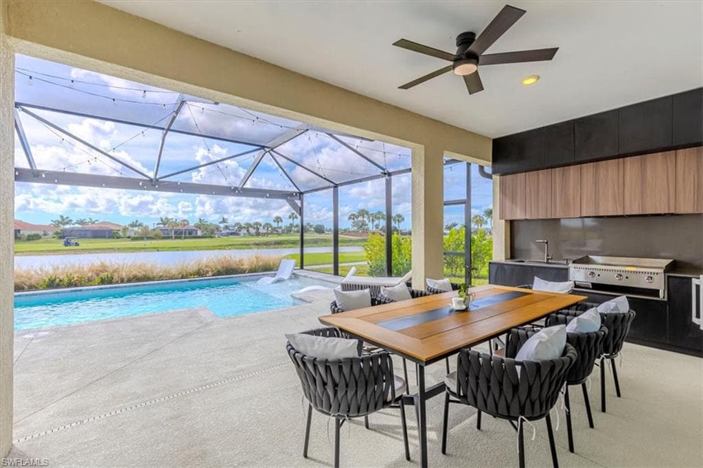 Swimming pool with a sunroom, a patio area, area for grilling, a water view, and outdoor dining area