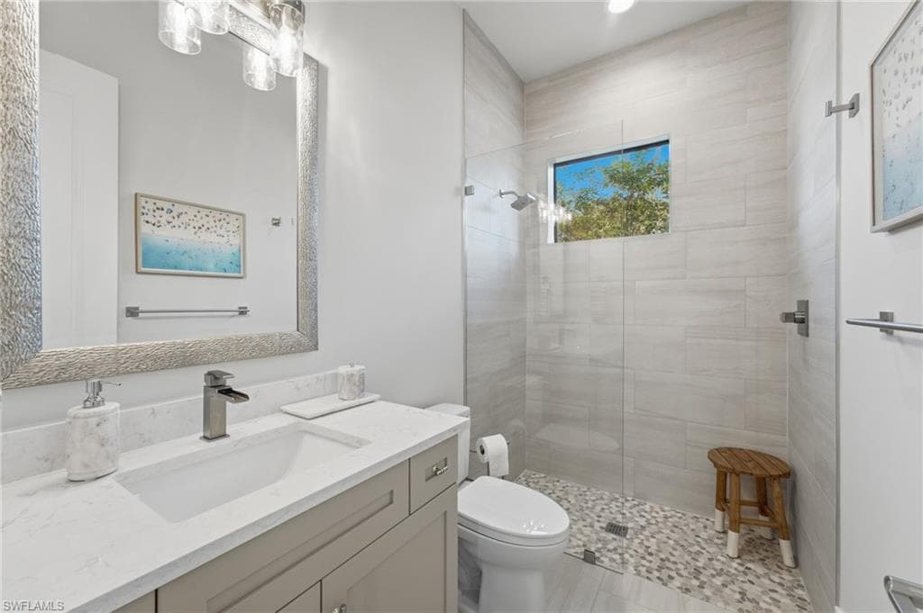 The fourth ensuite bath continues the home’s sophisticated design, featuring a sleek quartz-topped vanity, a spacious walk-in shower enclosed in seamless glass, and transom windows that invite natural light into this serene, spa-inspired retreat.