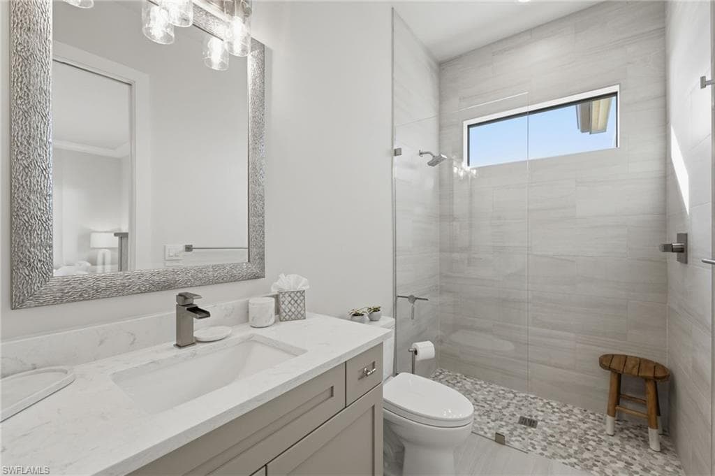 The third ensuite bath is elegantly appointed with a quartz-topped vanity and spacious walk-in shower enclosed by seamless glass. A thoughtfully placed transom window invites soft natural light, creating a bright and serene spa-like retreat.