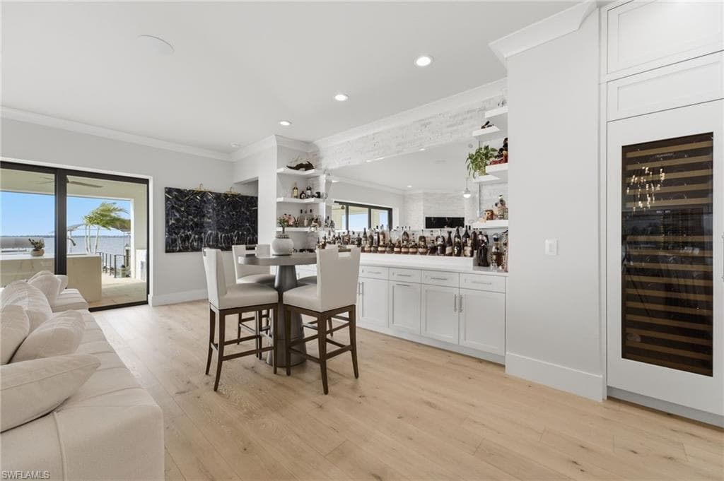 A sophisticated bourbon bar features a dramatic mirrored wall, artfully reflecting the shimmering water views and creating an elegant focal point for entertaining.