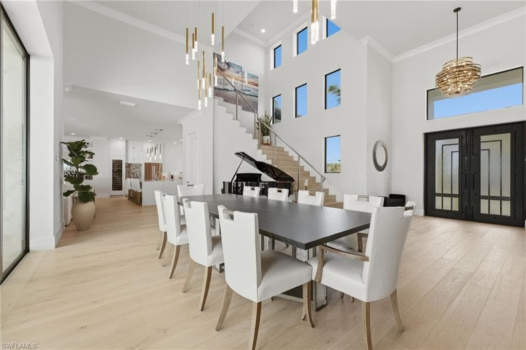 The elegant formal dining area, comfortably accommodating 10 guests, is introduced by custom wrought-iron hurricane-rated entry doors, while a beautifully appointed player piano adds timeless character and ambiance. Above, transom windows illuminate the dramatic cable-railed staircase, allowing natural light to cascade throughout the space and accentuate the home’s exceptional architectural details.
