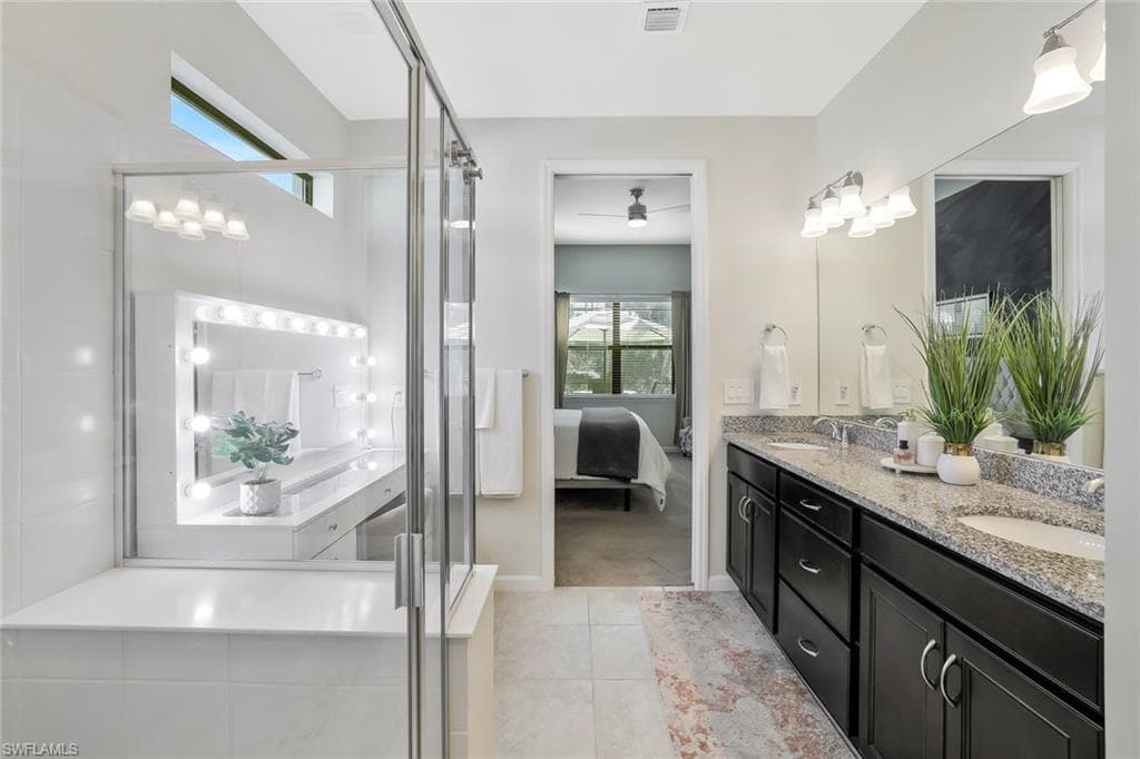 Bathroom featuring a double vanity with granite countertops, dark wood cabinetry, and dual sinks