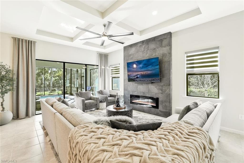 Spacious living area featuring a coffered ceiling, modern ceiling fan, and large format tile flooring