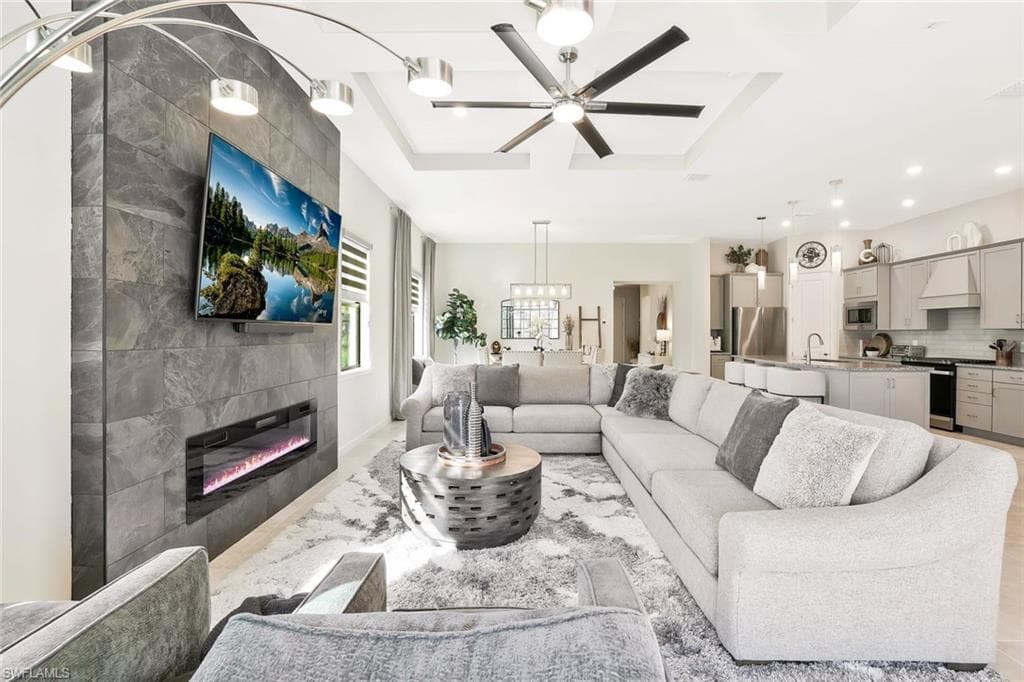 Open-concept living space featuring a modern fireplace with a slate-tile surround, built-in ceiling lighting, a tray ceiling, and hard-surface flooring
