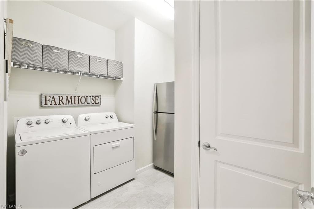 Dedicated laundry area featuring a washer and dryer set, wire shelving, and light-toned flooring